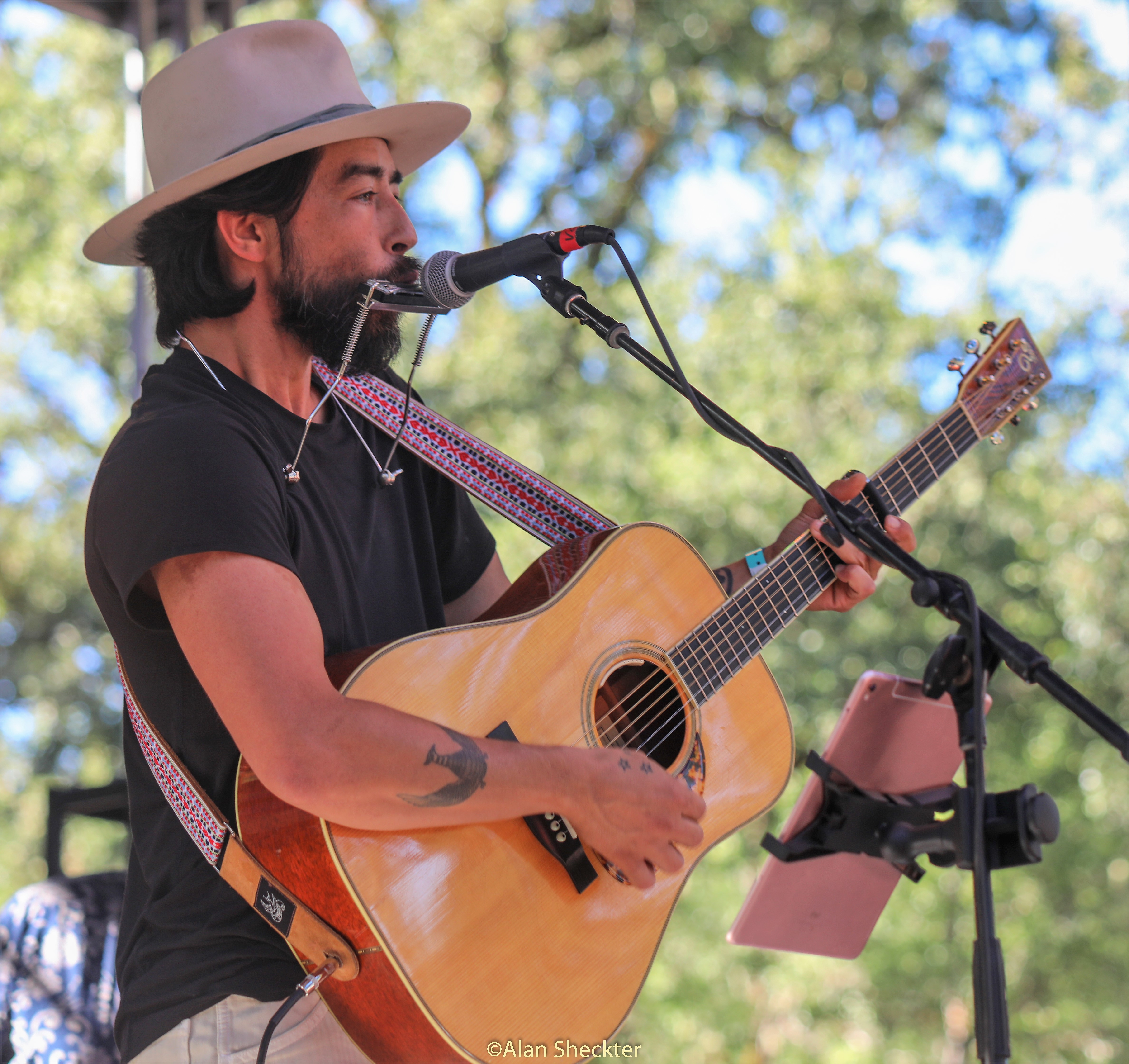 Jackie Greene strums on an acoustic guitar and plays harmonica early in his set on Sunday.