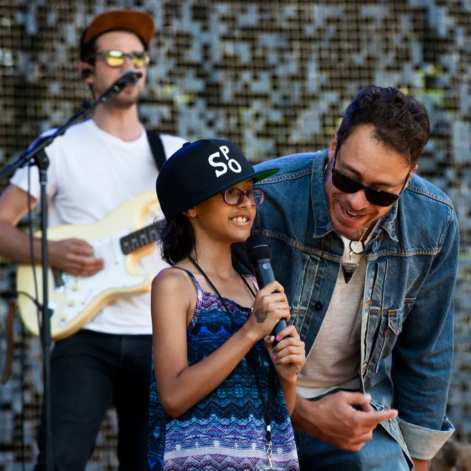 Amos Lee (right) is joined on stage by Melodic Caring Project rockSTAR Maya at a concert at Seattle’s Woodland Park Zoo in 2019