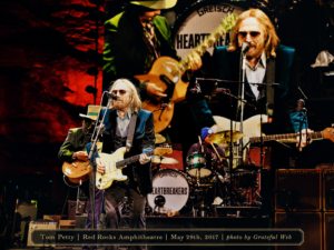 Tom Petty and the Heartbreakers perform on stage at Red Rocks, Tom Petty center stage with a cream guitar and sunglasses.