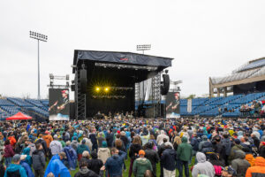 Outdoor concert at Westville Music Bowl with a full audience facing a large stage under overcast skies