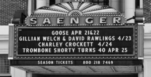 Vintage theater marquee in black and white with the word SAENGER in bulbs and a scrolling show list.