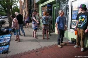 People line up outside a storefront with a lime-green façade and posters in the window.