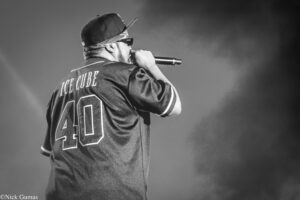 Ice Cube performing on stage, seen from behind, holding a microphone to his mouth.