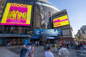 Crowd outside Madison Square Garden near the Chase entrance with a massive yellow Goose poster on the building facade