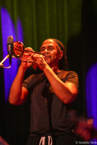 Jazz trumpeter performing on stage under colorful lights.
