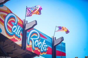 Colorful storefront with a retro sign and waving flags against a bright blue sky.