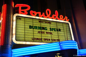 Close-up of a retro theater marquee with red neon script and a lit letter board showing 'FRI' and 'BURNING SPEAR'.
