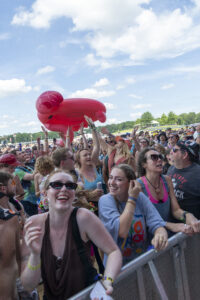 Crowd at outdoor festival reaching up to catch a large pink inflatable lobster.