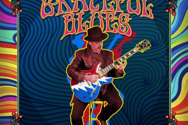 Guitarist in a maroon suit playing a blue zigzag guitar on a bright, psychedelic poster with red roses along the edges.