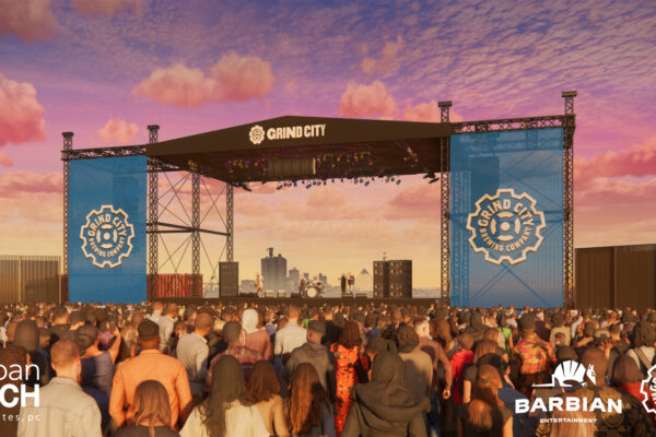 Outdoor music festival stage at sunset with a packed audience and blue banners bearing Grind City logos behind the performers.