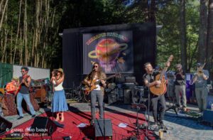 Live outdoor band performs on a red carpet stage in front of a forest backdrop with a colorful Terrapin Roadshow banner.