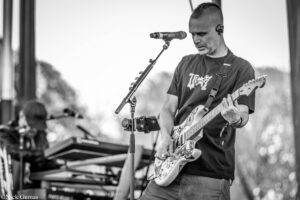 Guitarist performing on stage with a microphone in front of him.