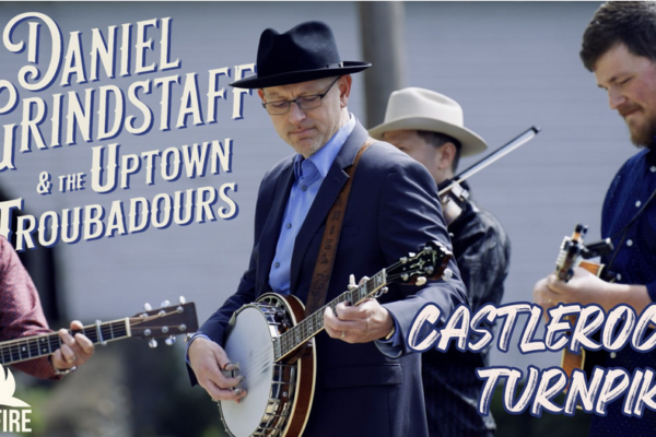 Promotional banner for a bluegrass band performing outdoors, with guitarists and a banjo, featuring Castlerock Turnpike and the Bonfire logo.