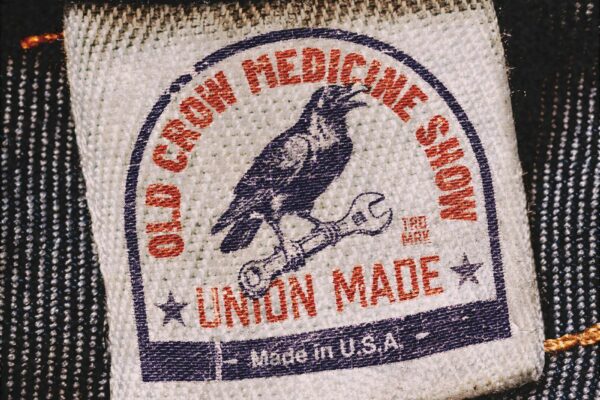 Close-up of a fabric clothing tag on denim, showing a circular stamp and the words 'Union Made' and 'Made in USA'.