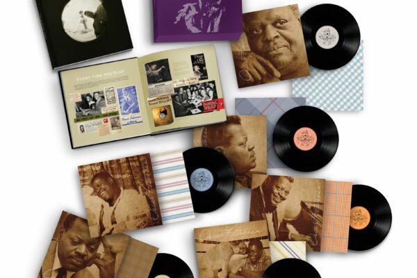 A flat lay of vintage vinyl records with paper sleeves featuring sepia portraits and patterned designs scattered around.