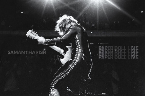 Black-and-white concert photo of Samantha Fish playing guitar on stage under bright overhead lights.